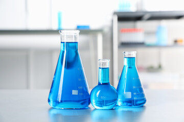 Flasks with light blue liquid on table in laboratory