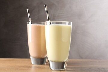 Tasty milkshakes in glasses on wooden table