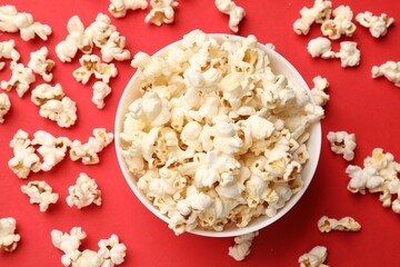 Tasty popcorn in bowl on red background, flat lay