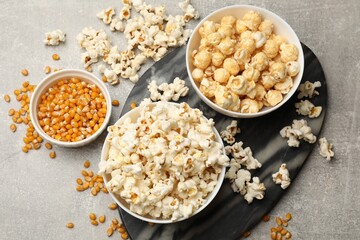 Tasty popcorn and corn kernels on light grey table, flat lay