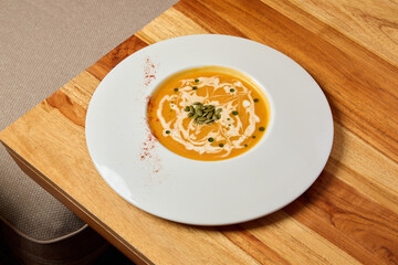 This dish has creamy pumpkin soup topped with a drizzle and garnish, a delightful experience