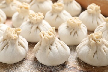 Uncooked khinkalis (dumplings) on wooden table, closeup