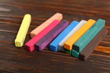 Colorful chalk pastels on wooden table, closeup