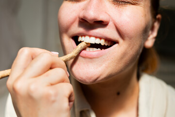A close-up of a woman's happy and confident smile while she uses a miswak stick. The shot captures...