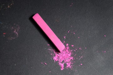 Pink chalk pastel on black table, top view. Space for text