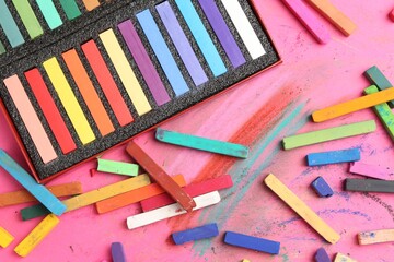 Many colorful chalk pastels on pink background, flat lay