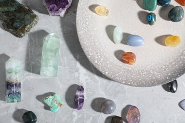 Many different healing stones on light grey table, flat lay