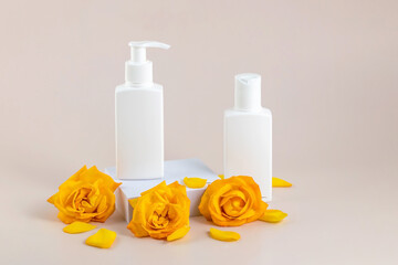 containers for skin care products on and yellow rose flowers on a beige background