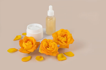 containers for skin care products on and yellow rose flowers on a beige background