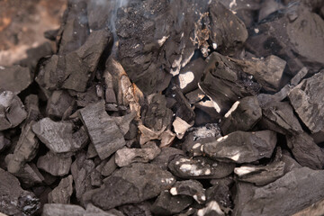 Black burning wood charcoal on a fire background.