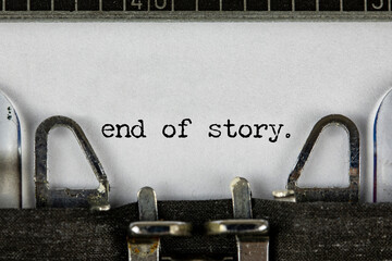 Closeup of a blue retro typewriter and the text the end written with it in a yellowish foil. Close...