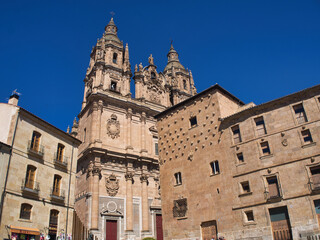 Fototapeta premium Clerecía of Salamanca and House of Shells: A low-angle view of the Pontifical University of Salamanca and a corner of the House of Shells against a clear blue sky.