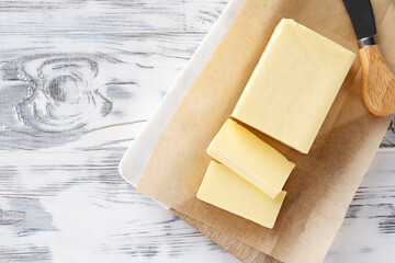 Sliced pieces of butter on a cutting board, white wooden background. Piece of butter.