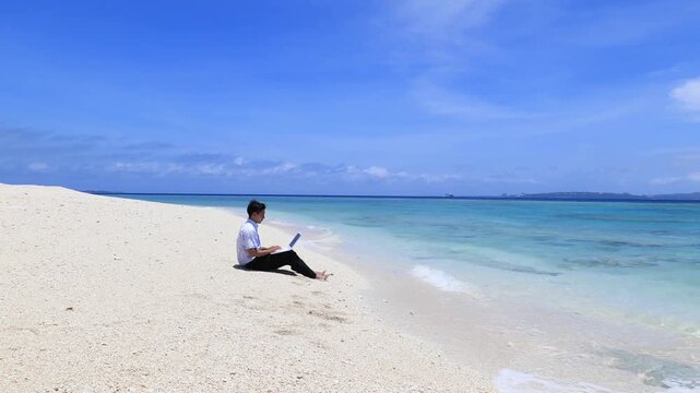 美しいビーチでパソコンを楽しむ笑顔の男性