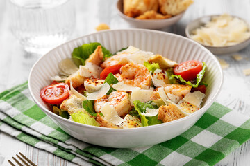 Classic Italian Caesar Salad with Shrimp on a white wooden background