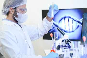 A scientist in protective gear conducts genetic research in a modern lab. He analyzes a chemical in...