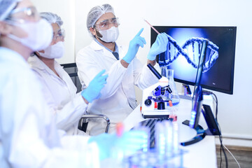 A diverse team of scientists collaborates in a genetics lab. A male researcher explains a procedure...