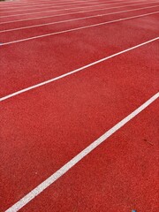Vibrant red athletic track with white lane lines offering a dynamic perspective for sports and competition concepts.