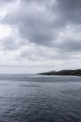 Vertical image off shore in the western Caribbean Sea ocean and land horizon on overcast gloomy day.
