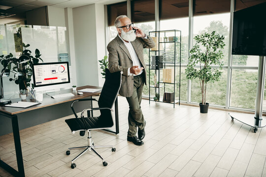 Confident senior male professional discussing a business strategy while on a call in a modern office environment