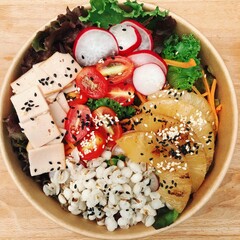 A vibrant salad bowl featuring greens, cherry tomatoes, radishes, carrots, grilled pineapple, and...