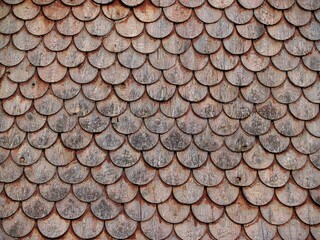 Close-up of traditional wooden shingle roof with weathered texture and repeating pattern.
