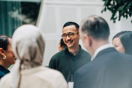 Smiling businessman interacting with entrepreneurs at networking event in convention center