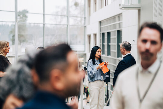Female entrepreneur discussing ideas with male colleague at networking event in convention center