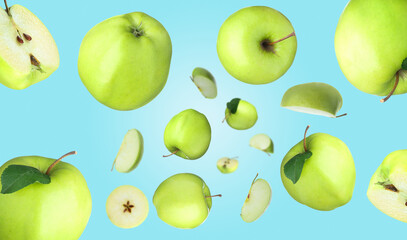 Fresh green apples swirling in air against light blue background