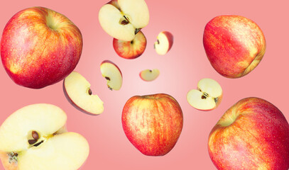 Fresh red apples swirling in air against pink gradient background