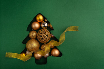 A collection of gold and bronze Christmas baubles arranged inside a green Christmas tree cutout, creating a festive and elegant holiday scene. Ideal for festive greeting cards, holiday banners