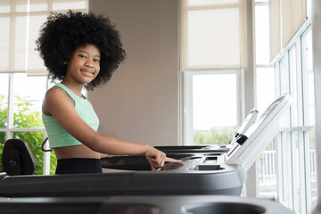 Teenage girl running on treadmill in gym. African American teenage girl   workout on treadmill in sport club