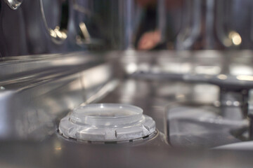 Close up of interior of stainless steel dishwasher with racks and wash arm.