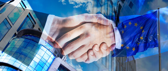 Business partners shaking hands against office buildings, multiple exposure with flag. Deal,...