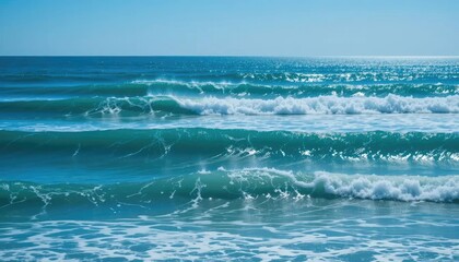 Fototapeta premium Ocean waves rolling towards the shore under a clear blue sky, creating a serene and calming seascape.