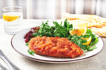 Milanese chicken, Crispy breaded chicken served, with fresh herbs, and lemon wedges,