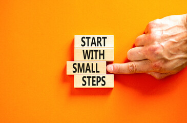 Start with small steps symbol. Concept words phrase Start with small steps on beautiful wooden blocks. Beautiful orange background. Businessman hand Business Start with small steps concept. Copy space