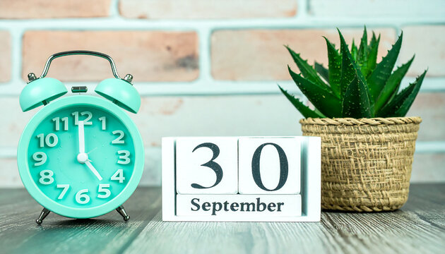 September 30 wooden block calendar with vintage clock and green plant