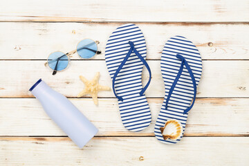 Striped blue flip flops with accessories on wooden background, top view
