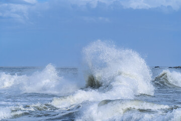 Puissantes vagues de l'oc&eacute;an Atlantique explosant en &eacute;cume blanche sous un ciel bleu nuageux. Sc&egrave;ne maritime naturelle et dramatique, symbole de la force de la mer.