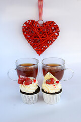 Chocolate cupcakes with cream cheese frosting with festive decorations and tea. Dessert for Valentine's Day or birthday. A wonderful festive treat for a wedding or children's party.