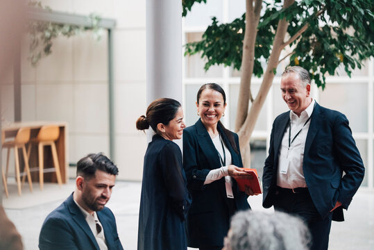 Happy male and female business professionals networking at convention center