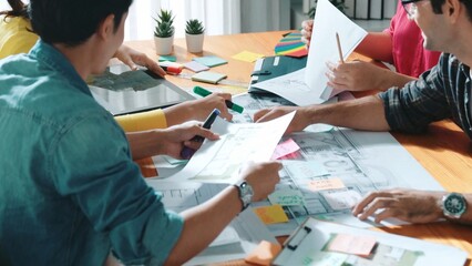 Top view of skilled civil engineer team writing at blueprint and planning design. Professional architect engineer working together sharing idea and taking a note in project plan at table. Symposium.