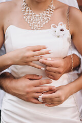 Close-up wedding photo of bride and groom putting gold rings on their fingers during the ceremony.