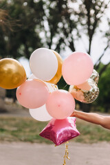 Close up photo of colorful balloons in woman's hands outdoors on birthday celebration.