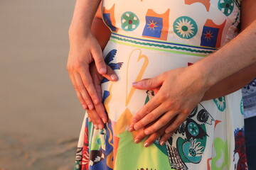 Femme enceinte gros plan sur le ventre avec mains en forme de coeur