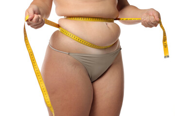 Studio shot of obese woman squeezing waist fat with tape measure for weight loss and body...