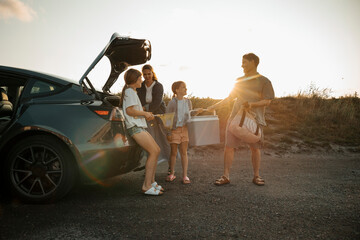 Father enjoying with daughter while unloading car trunk at sunny day