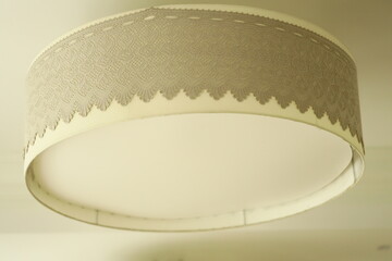 A lamp shade hangs from the ceiling in a cozy room, providing warm lighting
