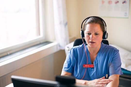 High angle view of female medical expert wearing headset explaining while giving online consultation through computer in